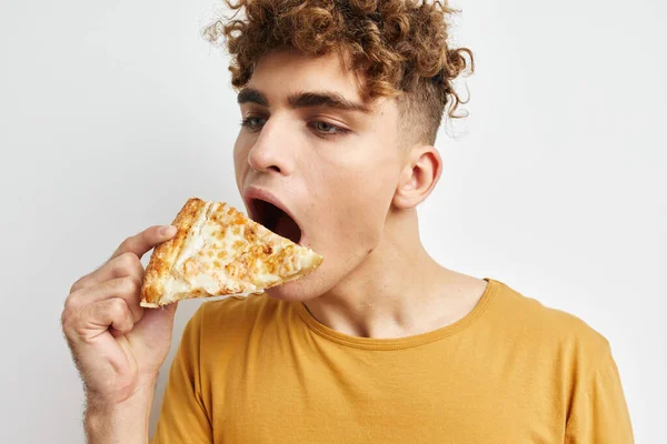 英俊的年轻人正在吃比萨饼，摆出一副特写镜头的样子，生活方式保持不变 — 图库照片