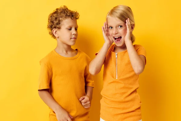 Leuke kleuters in gele t-shirts die naast elkaar staan emoties uit hun kindertijd gele achtergrond onveranderd — Stockfoto
