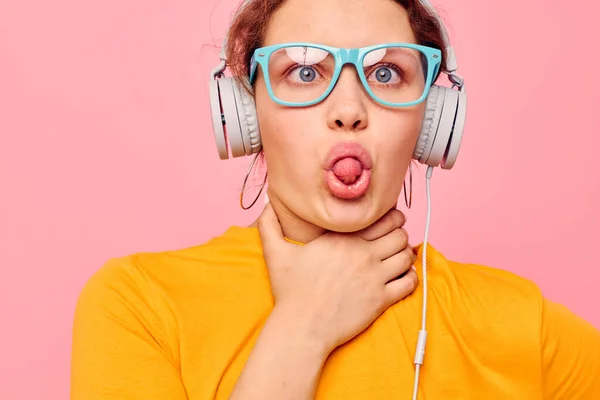 Femme gaie portant des lunettes bleues écoutant de la musique sur des écouteurs milieux isolés inchangés — Photo