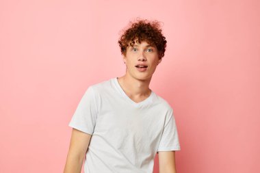 Kırmızı kıvırcık saçlı, yaz kıyafetleri giyen beyaz tişörtlü, izole edilmiş arka plan pozu veren adam.