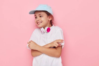 Beyaz tişörtlü, pembe şapkalı, gülümseyen kız kulaklığı portresi