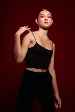 Seksi esmer kadın siyah tişört, pembe makyaj makyaj, pembe arka plan değiştirilmemiş.