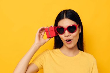 Çekici genç Asyalı kadın moda gözlükleri hediye sarı arka plan değiştirilmemiş