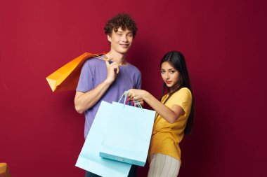 Gençler renkli çantalar alışverişte eğlenceli kırmızı arka plan değiştirilmemiş