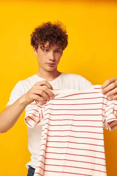 Cute berambut merah pria di t-shirt putih memegang bergaris t-shirt gaya pemuda mode latar belakang terisolasi — Stok Foto