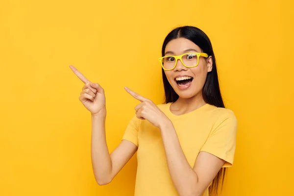 stock image Charming young Asian woman in yellow t-shirts with glasses posing fashion yellow background unaltered