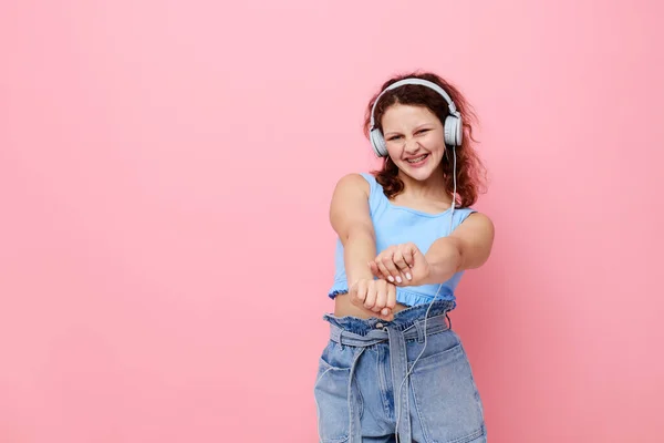 Chica usando auriculares danza movimiento entretenimiento rosa fondo inalterado — Foto de Stock