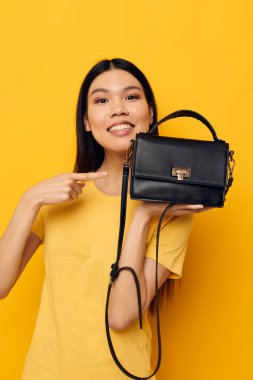 Sarı tişörtlü güzel kadın siyah çantalı poz veren moda.