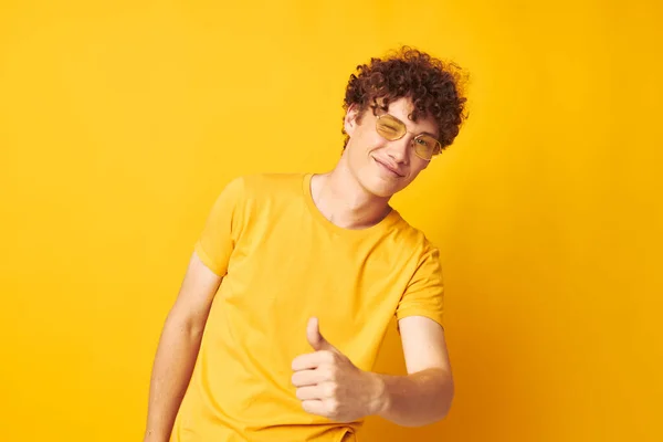 Ragazzo con i capelli rossi ricci giallo t-shirt occhiali moda gesti mano giallo sfondo inalterato — Foto Stock