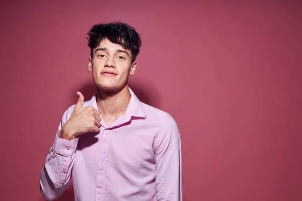 Pretty man in a pink shirt gesturing with his hands pink background unaltered — Stockfoto