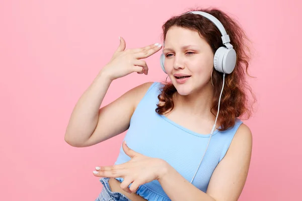 Fille gaie portant des écouteurs posant geste avec les mains fond rose inchangé — Photo