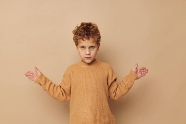 Bej kazaklı genç bir çocuğun fotoğrafı. Eğlenceli poz veriyor. Yaşam tarzı değişmemiş.