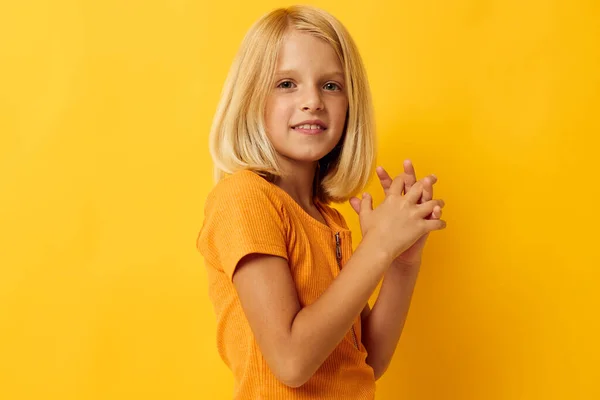 Sarı tişörtlü küçük bir kızın portresi. Stüdyoda çocukluk yaşam tarzını değiştirmeden poz veriyor. — Stok fotoğraf