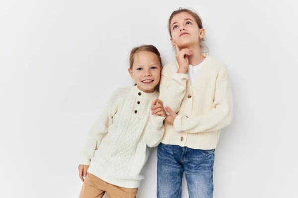 Two little girls in sweaters posing childhood light background — Zdjęcie stockowe
