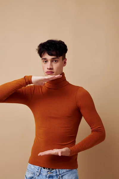 Un joven posando en suéter marrón confianza en sí mismo moda luz fondo inalterado —  Fotos de Stock