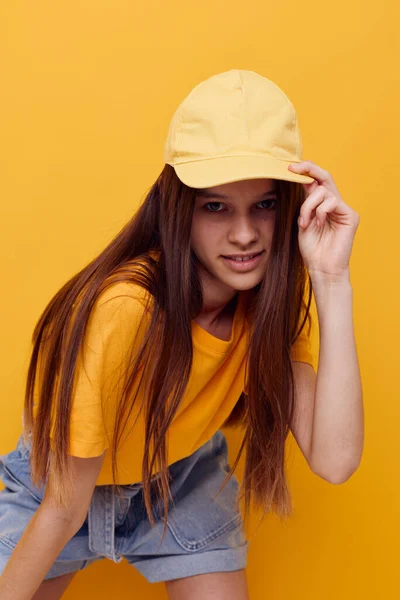 Foto bonita mulher posando em uma camiseta amarela e tampa isolado fundo — Fotografia de Stock