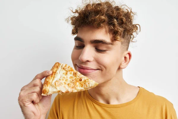 ハンサムな男食べるピザポーズクローズアップ光の背景 — ストック写真