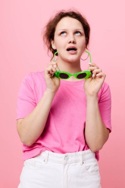 Pembe tişörtlü, yeşil gözlüklü genç kız mankeni. Gençlik modası.