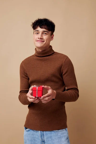 Handsome guy brown turtleneck posing fashion small gift box light background unaltered — Stock Photo, Image