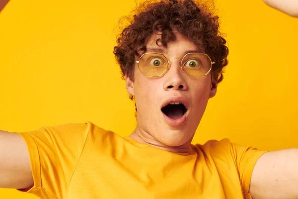 Mladý kudrnatý muž žluté tričko brýle módní ruka gesta izolované pozadí beze změny — Stock fotografie