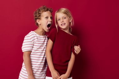 Neşeli çocuklar gülümseyerek ve rahat bir şekilde poz vererek izole edilmiş arka plana bakıyorlar.