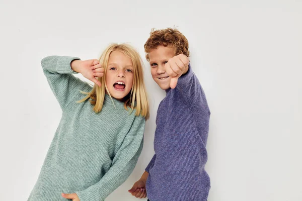 Portrét roztomilé děti v multi-barevné svetry pózující pro zábavu lehké pozadí — Stock fotografie