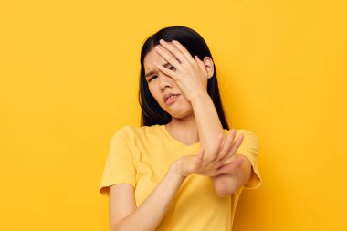 Sarı tişörtlü güzel esmer, kafasından memnun olmayan stüdyo modelini tutuyor.