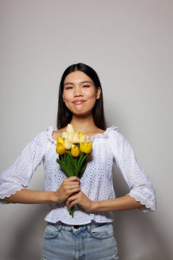 Beyaz gömlekli güzel bir esmer. Çiçekler baharda değişmemiş arka plan pozu veriyor.