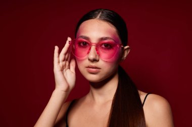 Güzel moda bayan pembe gözlüklü parlak makyajlı siyah formalı pembe arka plan değiştirilmemiş.