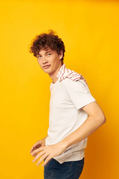 Ragazzo con i capelli rossi ricci in una t-shirt bianca tiene una t-shirt a righe stile giovanile stile giallo sfondo inalterato — Foto Stock