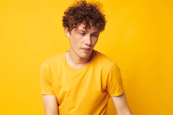 Retrato de un joven rizado con elegante camiseta amarilla posando fondo amarillo inalterado — Foto de Stock