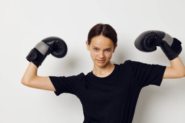 Siyah pantolonlu boks eldivenli atletik bir kadın ve bir tişört fitness eğitimi.