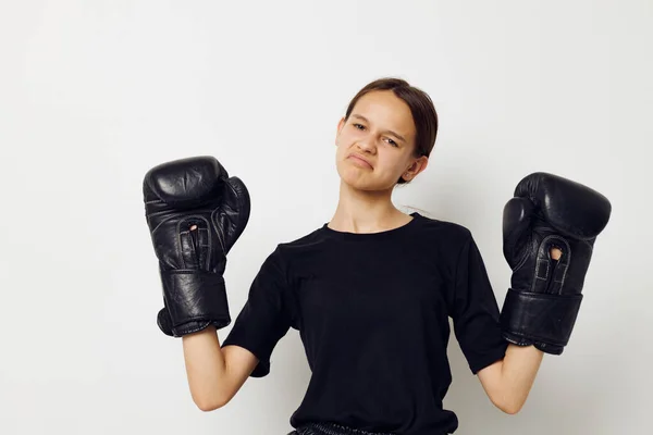 Atletische vrouw in zwart sport uniform bokshandschoenen poseren geïsoleerde achtergrond — Stockfoto