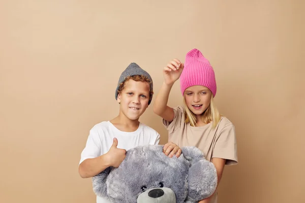 Portrait of cute children in hats with a teddy bear friendship isolated background — Fotografia de Stock