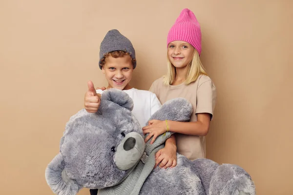 Photo of two children in multi-colored hats entertainment posing beige background — Fotografia de Stock