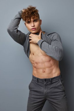 Gri tişörtlü şık bir adam. Moda stüdyosu. Gri arka plan.