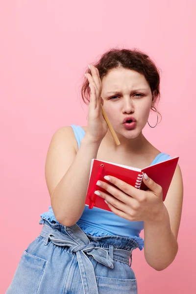 Jolie femme dans un T-shirt bleu avec un bloc-notes rouge et un stylo d'émotions fond isolé inchangé — Photo