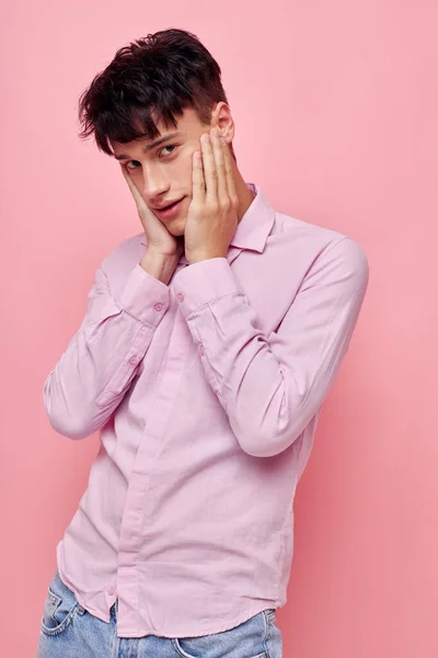 Mladý muž v růžové košili gestikuluje s rukama růžovým pozadím beze změny — Stock fotografie