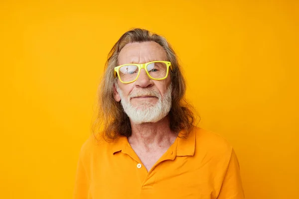 Foto de anciano retirado camiseta amarilla y gafas posando en forma de corazón caja fondo amarillo — Foto de Stock