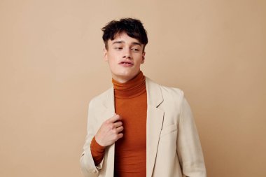 Genç bir erkek arkadaş, elinde telefonla şık bir model stüdyosunda poz veriyor.