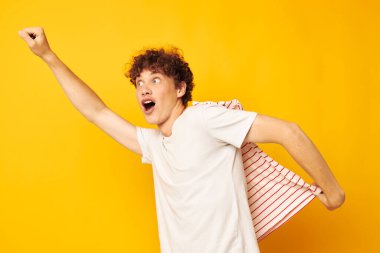 Beyaz tişörtlü, kırmızı kıvırcık saçlı adamın elinde çizgili bir gençlik tarzı var.