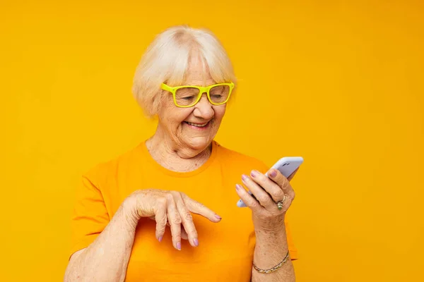 은퇴 한 할머니의 재미있는 사진 전화노란 배경에 대 한 이야기 — 스톡 사진