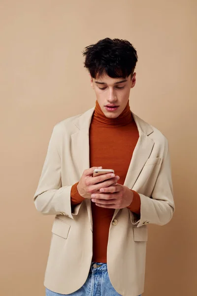 Portrait of a young man in a beige jacket talking on the phone light background unaltered — Stock fotografie