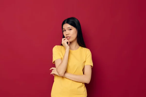 Charmig ung asiatisk kvinna i en gul t-shirt gest med händerna roliga studio modell oförändrad — Stockfoto