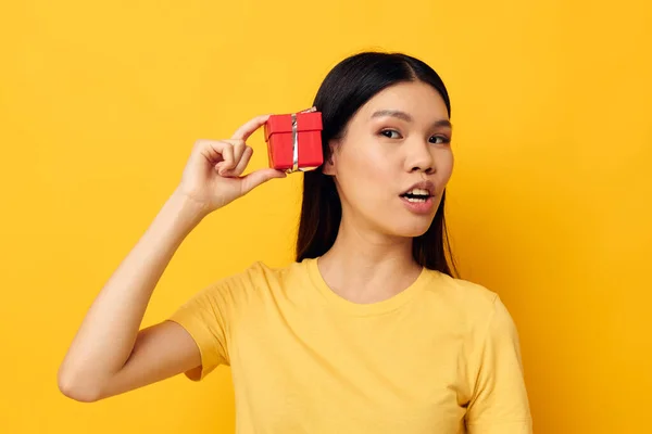 Affascinante giovane donna asiatica in una t-shirt gialla regalo di vacanza emozioni modello studio inalterato — Foto Stock