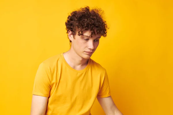 Молодий кучерявий чоловік Молодіжний стиль окуляри студія повсякденний одяг жовтий фон незмінний — стокове фото