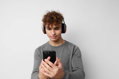 Elinde telefonla kulaklıkla müzik dinleyen çekici bir adam.