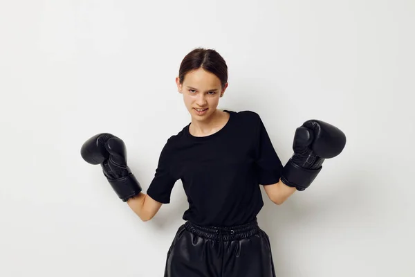 Mujer atlética en negro deportes uniforme guantes de boxeo posando fondo aislado —  Fotos de Stock