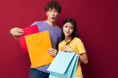 Genç erkek ve kız alışveriş torbaları el ele tutuşturulmuş, değiştirilmemiş arka plan