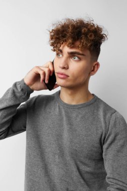 Yakışıklı genç adam telefonda konuşuyor. Duygularını dışa vuruyor.